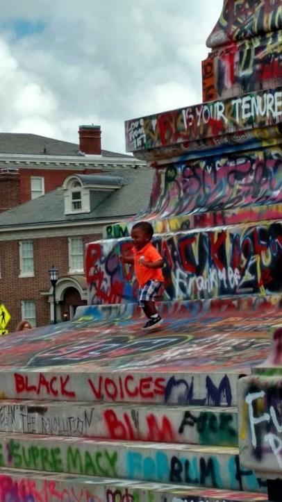 Young African-American toddler running around statue